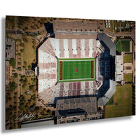 An aerial view of a football stadium with a green field, surrounding buildings, and parking areas.