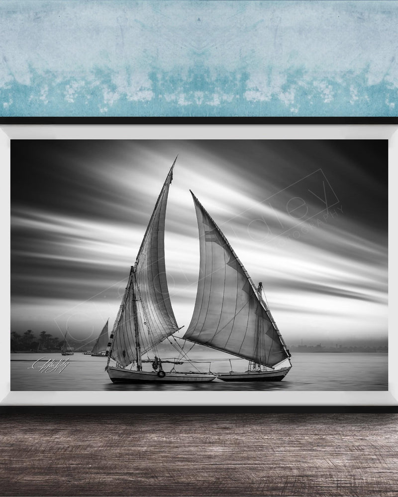 This luxury black and white fine art photograph captures a felucca sail boat drifting along the Nile River at sunset near Luxor, Egypt. Soft fog and minimalist composition create a timeless, monochrome aesthetic rooted in Egyptian river culture. Ideal for collectors and interior designers seeking refined, museum-quality wall art that embodies elegance, simplicity, and enduring calm. black white nile river art, felucca sailboat wall decor, luxor egypt monochrome print, luxury minimalist wall art