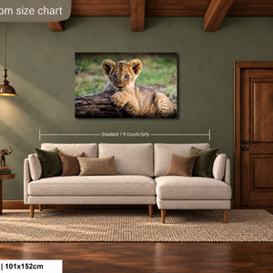 a living room with a large sofa, a wooden door, and a painting of a young lion resting on a log.