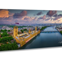 a cityscape with a large, ornate building with a distinctive yellow facade, situated along a river. The sky is filled with clouds, creating a dramatic backdrop for the scene. The city appears to be London, with the Houses of Parliament and other buildings visible in the background.