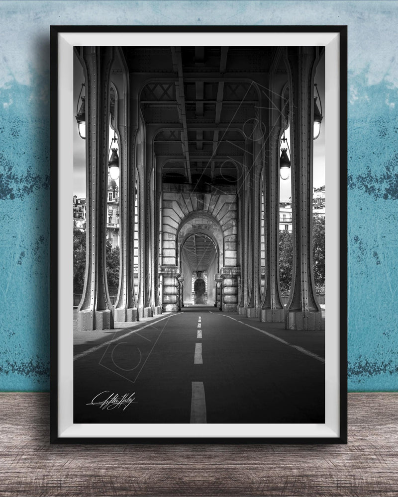 A black and white photograph of a long, narrow hallway with tall columns and arches, leading to a doorway at the end. The hallway appears to be part of a larger architectural structure, possibly a building or a church.