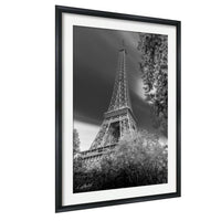 A black and white photograph of the Eiffel Tower in Paris, France, with a cloudy sky in the background.