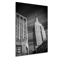 A black and white photograph of the Empire State Building, a famous skyscraper in New York City, with a cloudy sky in the background.