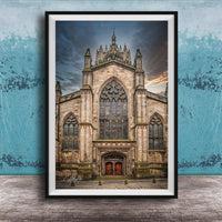 A framed photograph of a Gothic cathedral with a large rose window and a tall spire, set against a cloudy sky.