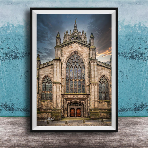 A framed photograph of a Gothic cathedral with a large rose window and a tall spire, set against a cloudy sky.