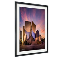a modern, curved building with a unique architectural design, set against a vibrant sunset sky.