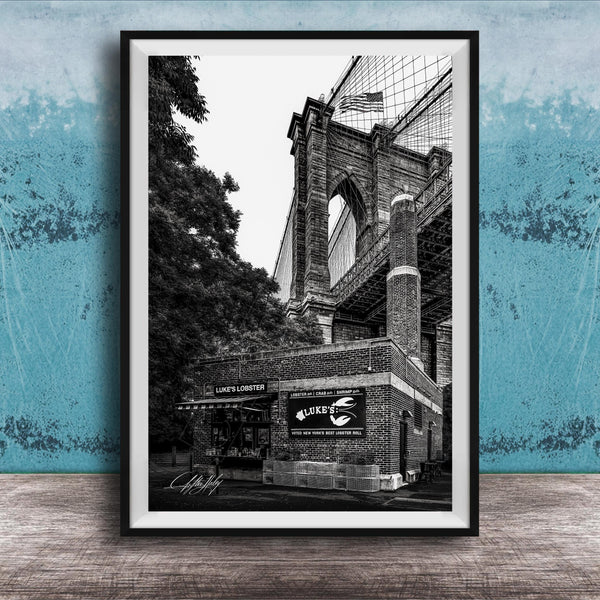 A black and white photograph of the Brooklyn Bridge, with the name 'LOOKS LOBSTER' displayed on the building.