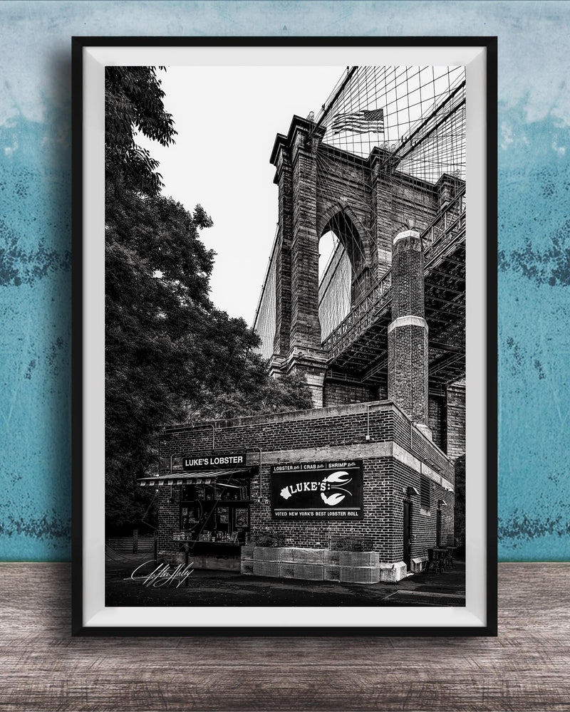 A black and white photograph of the Brooklyn Bridge, with the name 'LOOKS LOBSTER' displayed on the building.