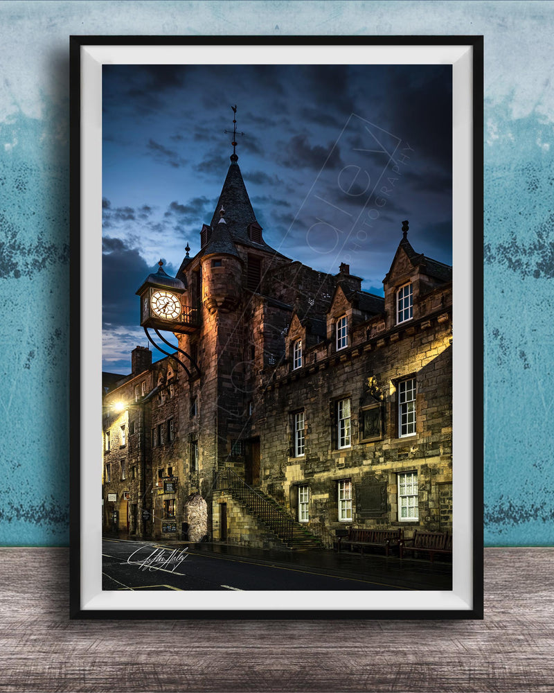 a historic stone building with a clock tower, set against a dark sky with clouds.