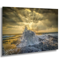 a dramatic scene of a powerful wave crashing against a rocky shore, with the sun's rays shining through the clouds and creating a stunning, golden glow over the ocean.