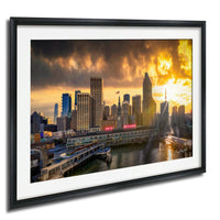 a cityscape with tall buildings and a body of water, possibly a river or bay, during a dramatic sunset.