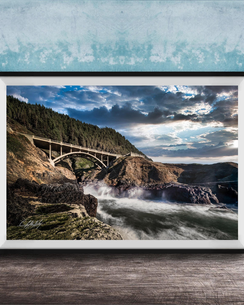 a scenic view of a bridge spanning over a rushing river, with a dramatic sky and lush green trees in the background.