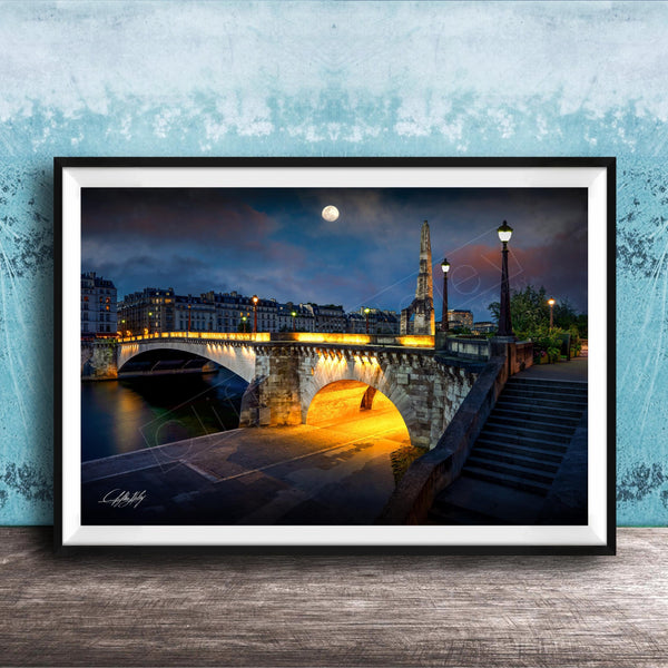 a picturesque night scene of a bridge illuminated by warm lighting, with a full moon in the sky and a tall spire in the background.