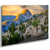 a breathtaking view of a mountainous landscape at sunset, with a large, snow-capped peak in the distance and a rocky outcropping with a tree growing on it in the foreground.