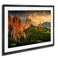 a breathtaking landscape with towering red rock formations silhouetted against a vibrant sunset sky, surrounded by lush greenery and a distant mountain range.