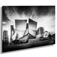 A striking black and white photograph of the Walt Disney Concert Hall in Los Angeles, California, showcasing its unique architectural design and dramatic sky.
