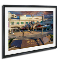 A bronze statue of a horse and jockey racing on a track, with the name "Barbaro" inscribed on a pedestal in front of the building.