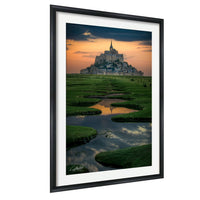 a picturesque castle situated in a lush green field, with a serene body of water reflecting the castle and the sky in the background.