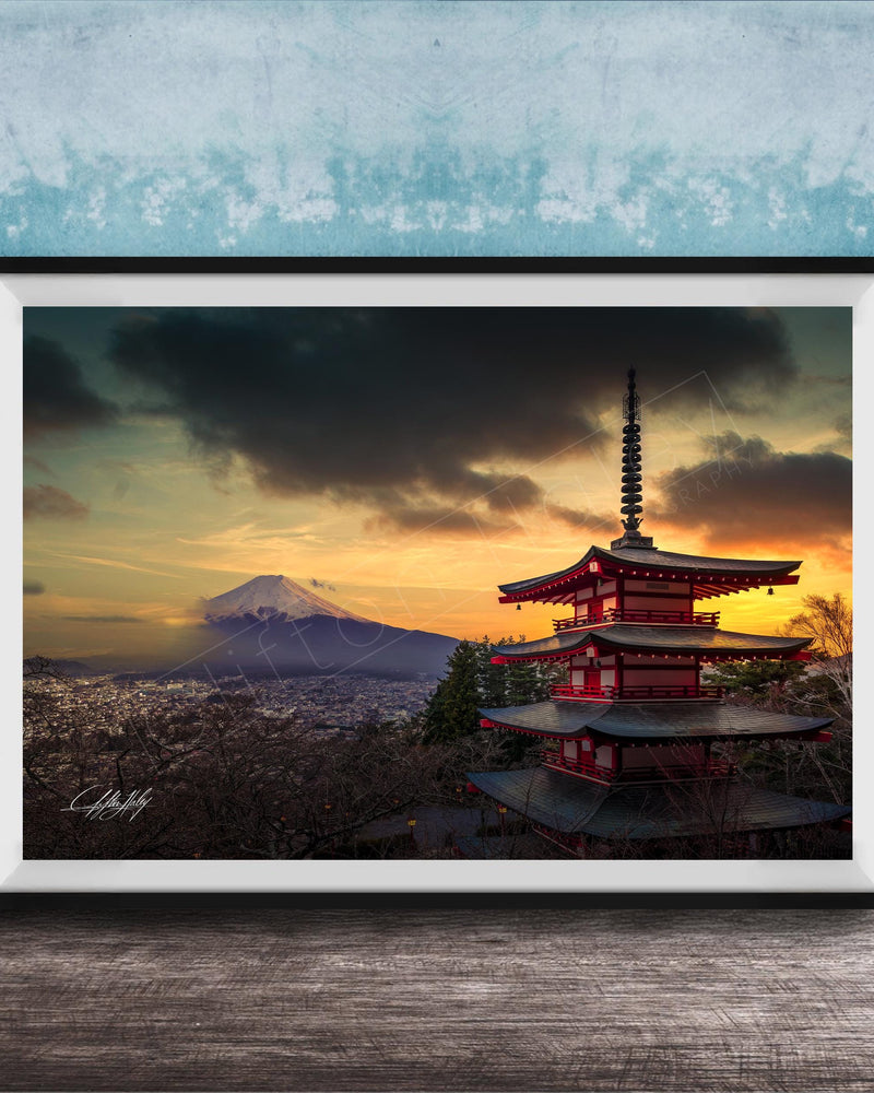 A framed photograph of the Mount Fuji, a famous landmark in Japan, with a red pagoda-style building in the foreground and a dramatic sky in the background.