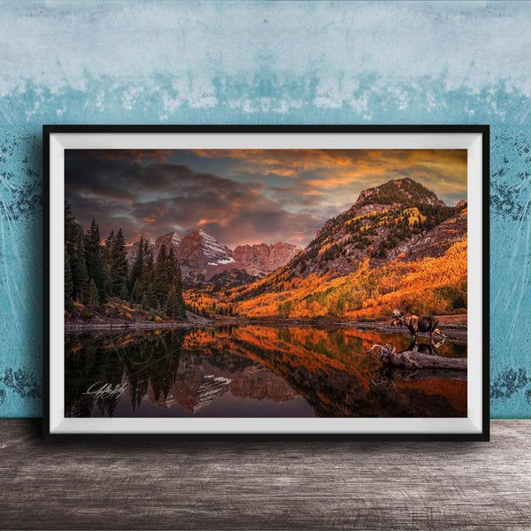 The image is a framed photograph depicting a serene mountain landscape with a lake, trees, and mountains in the background, reflecting the vibrant colors of the sky.