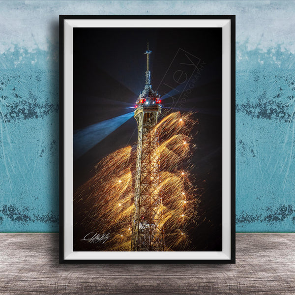 A framed photograph of the Eiffel Tower with a fireworks display in the background, creating a vibrant and colorful scene.