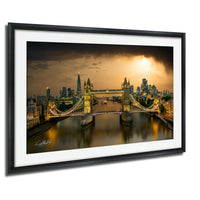 A framed photograph of the Tower Bridge in London, England, with the city skyline and the River Thames in the background, illuminated at night.