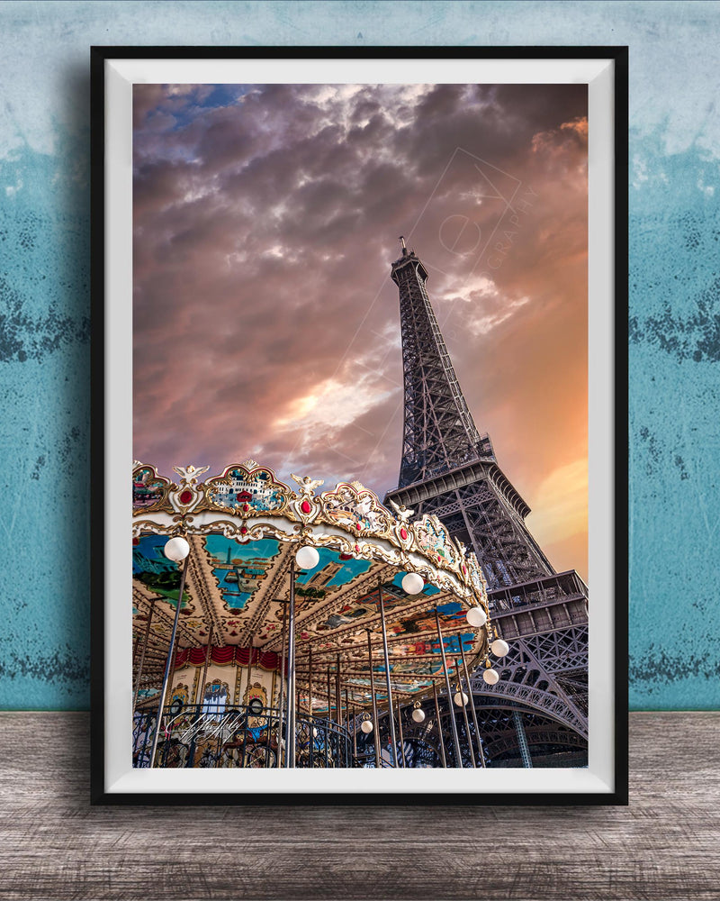 A framed photograph of the Eiffel Tower and a colorful carousel, set against a dramatic sky with clouds.
