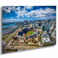 An aerial view of a large baseball stadium surrounded by a cityscape, with tall buildings and a body of water in the background.