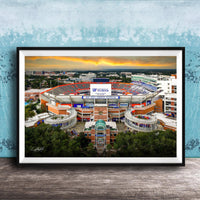 The image is a framed photograph of the Ben Hill Griffin Stadium inUF, Florida, with a sunset sky in the background.