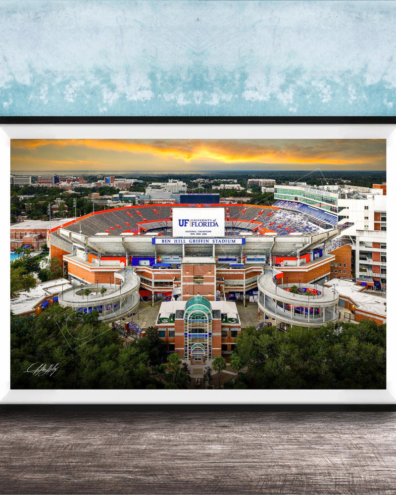 The image is a framed photograph of the Ben Hill Griffin Stadium inUF, Florida, with a sunset sky in the background.