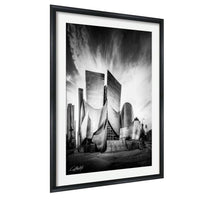 A black and white photograph of a modern, curved building with a distinctive architectural design, framed and displayed on a wall.
