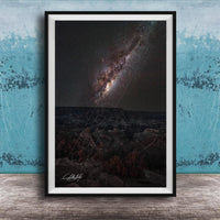 The image is a framed photograph of a night sky with a distant galaxy, set against a dark background.