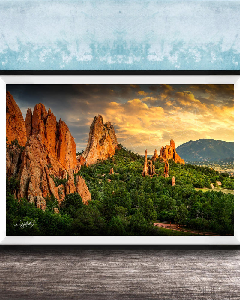 A framed photograph of the Garden of the Gods, a famous rock formation in Colorado, with its distinctive red rock formations and lush green vegetation.