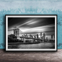 A black and white photograph of the Brooklyn Bridge in New York City, with the city skyline in the background.