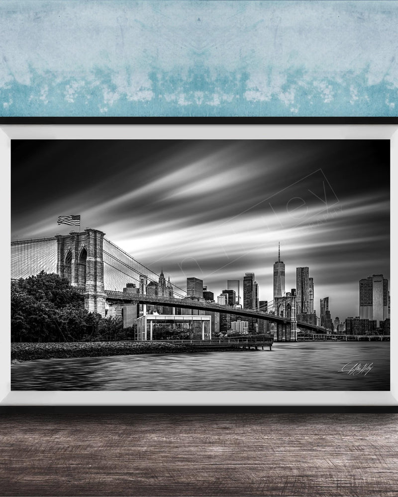 A black and white photograph of the Brooklyn Bridge in New York City, with the city skyline in the background.