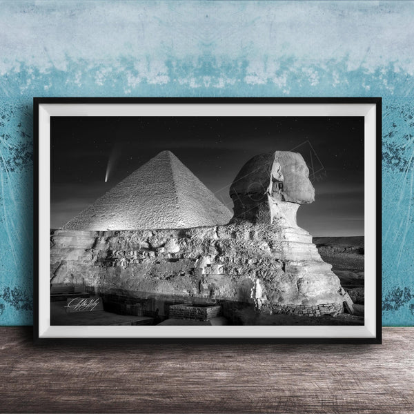 A black and white photograph of the Great Sphinx and the Pyramid of Giza against a night sky, with a small shooting star visible in the sky.