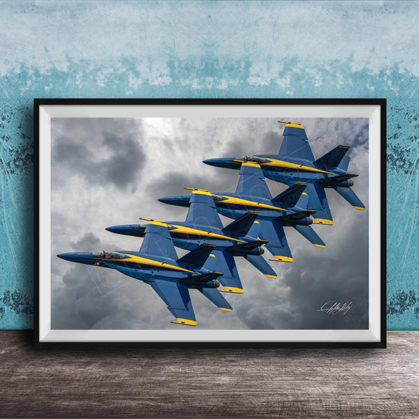 A framed photograph of four blue and yellow fighter jets flying in formation against a cloudy sky.