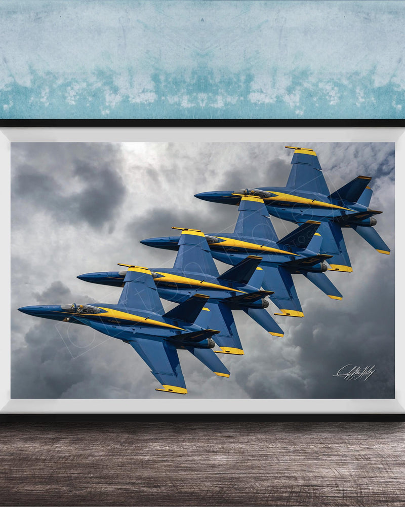 A framed photograph of four blue and yellow fighter jets flying in formation against a cloudy sky.