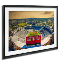The image is an aerial view of a large sports stadium, specifically a football stadium, with a cityscape in the background.