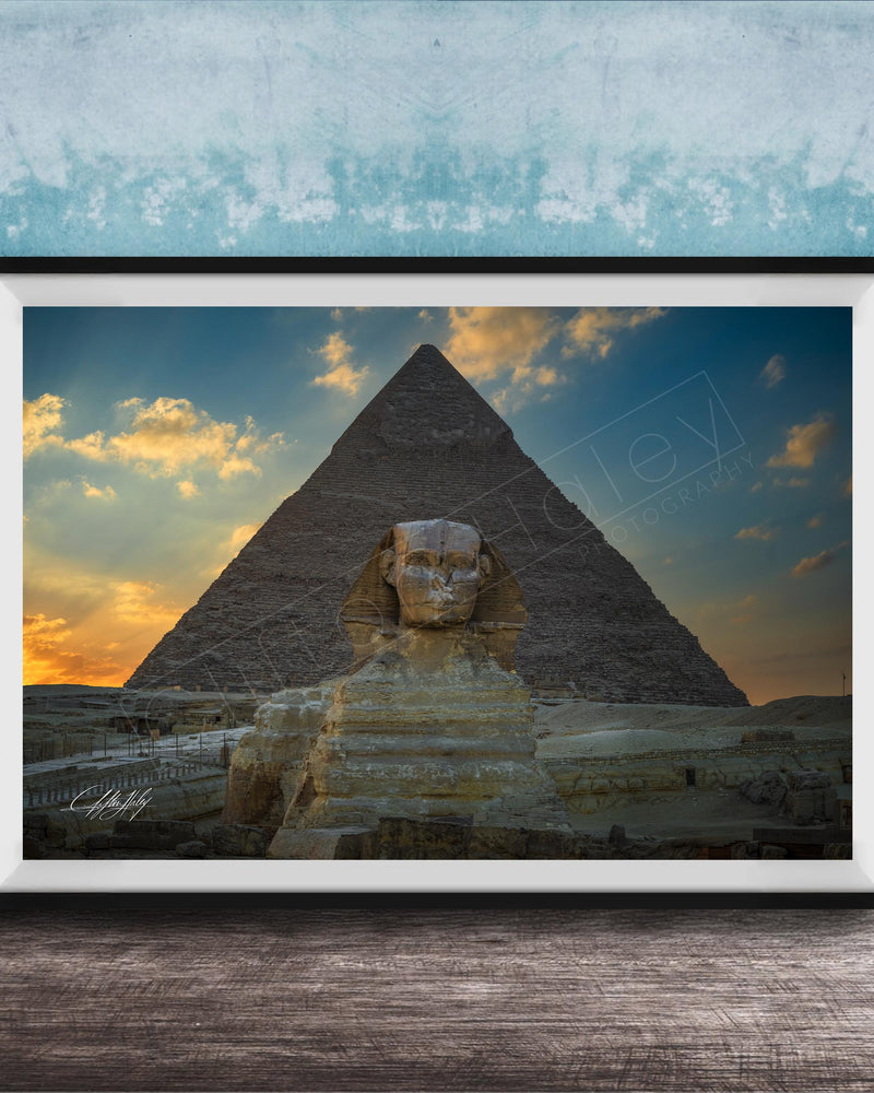 a large, ancient Egyptian pyramid with a sphinx statue in the foreground, set against a colorful sunset sky.