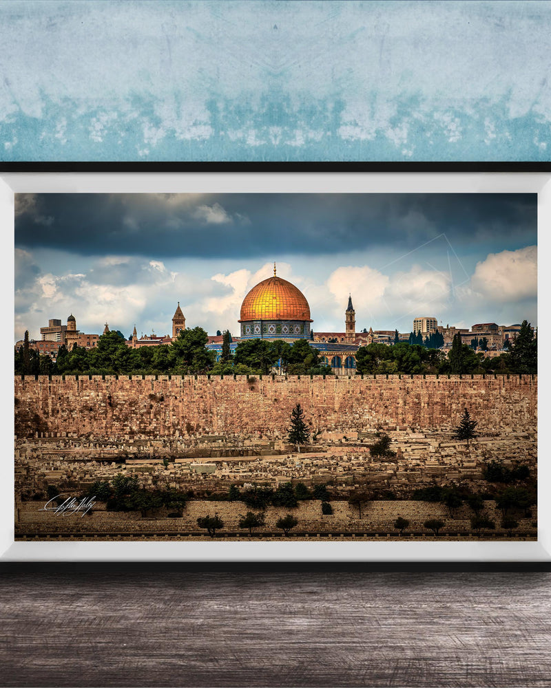 the Dome of the Rock, a significant landmark in Jerusalem, Israel. The photograph is framed and displayed on a wooden surface, showcasing the architectural beauty of the structure against a cloudy sky.