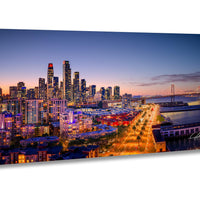 A stunning aerial view of a city skyline at dusk, with the buildings illuminated in vibrant colors against a deep blue sky.