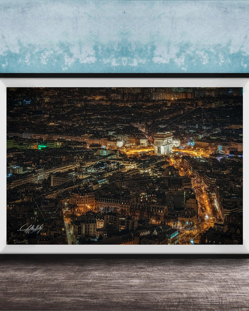 The image is a framed aerial view of a city at night, showcasing the illuminated buildings and streets below.