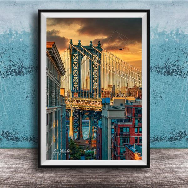 The image is a framed photograph of the Manhattan Bridge in New York City, with the bridge and surrounding buildings illuminated by a colorful sunset sky.