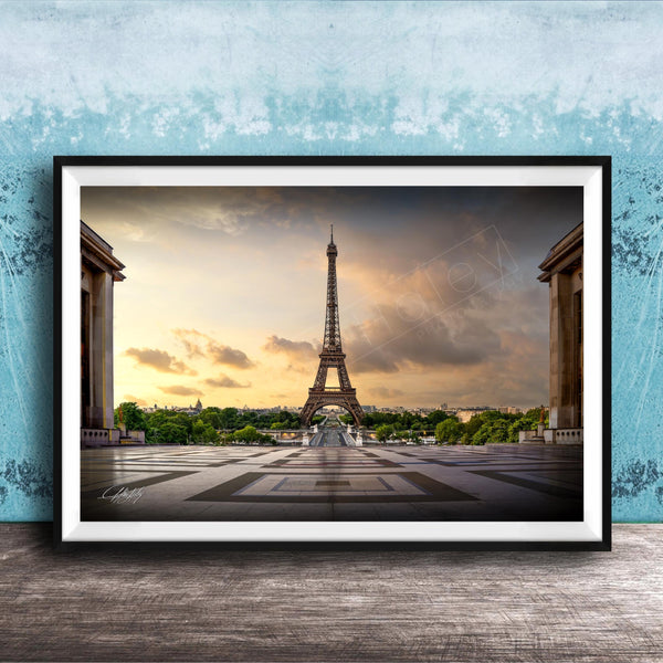 a framed photograph of the Eiffel Tower in Paris, France, with a dramatic sky in the background.