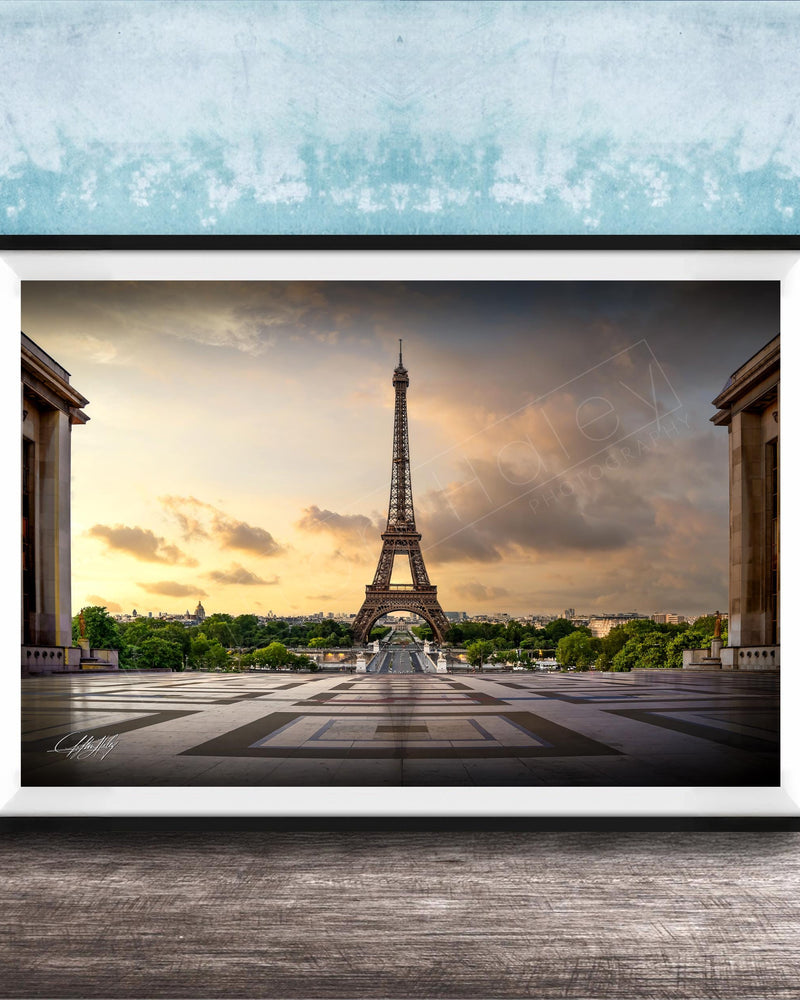 a framed photograph of the Eiffel Tower in Paris, France, with a dramatic sky in the background.