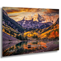 A breathtaking mountain landscape with a serene lake in the foreground, surrounded by vibrant autumn foliage. The sun is setting behind the mountains, casting a warm glow over the scene.