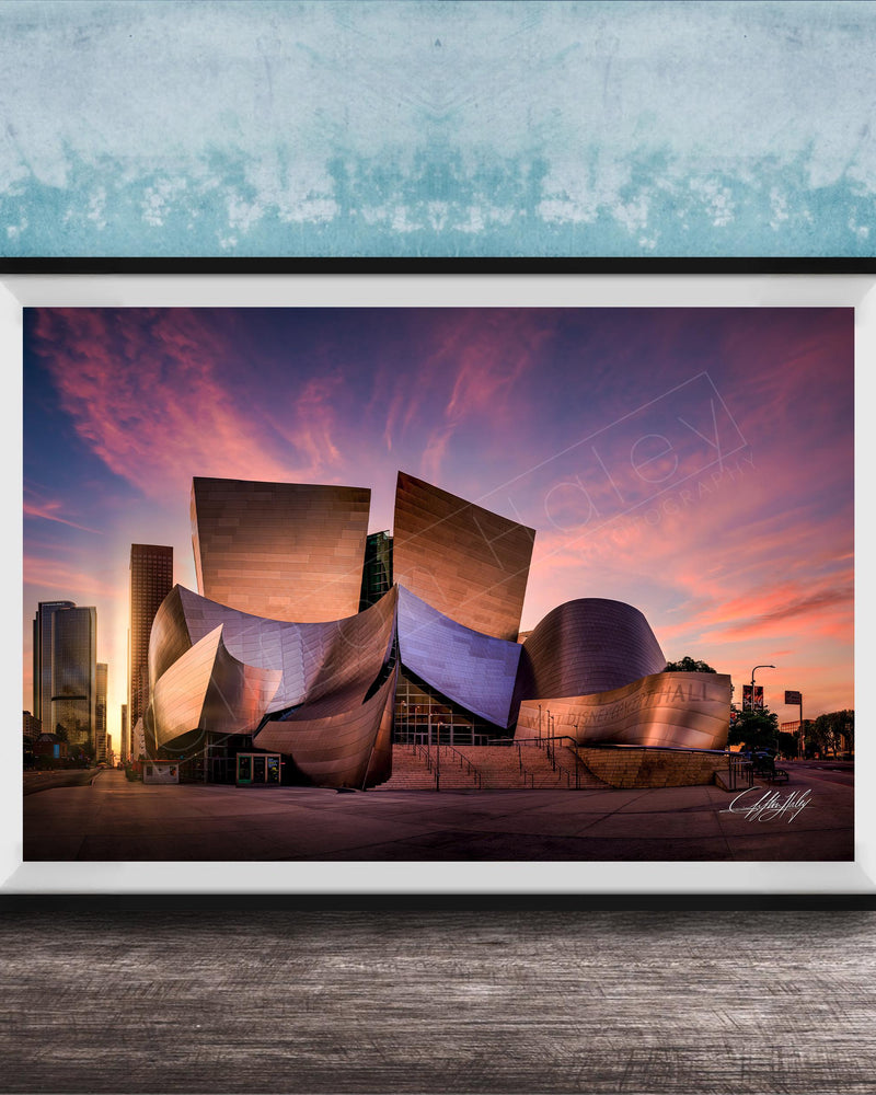 A framed photograph of the Guggenheim Museum in Bilbao, Spain, at sunset, with the distinctive curved architecture of the building illuminated against a colorful sky.