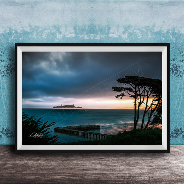 a serene coastal scene at sunset, with a wooden pier extending into the calm, blue waters. The sky is filled with clouds, creating a dramatic backdrop for the tranquil setting.