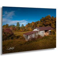 a rustic wooden barn nestled in a lush, green field, surrounded by a vibrant display of autumn foliage.